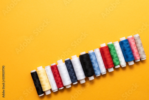 colored sewing threads on yellow background