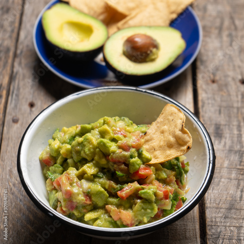 Mexican guacamole with tomato on wooden background