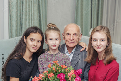 family celebrates birthday while sitting with bouquet of flowers at home