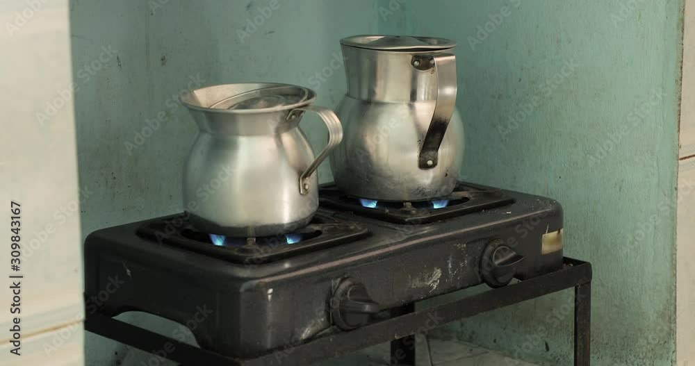 Heating milk and water for making coffee on an old metal stove in metal jugs Heating milk and water for making coffee on an old metal stove in metal jugs