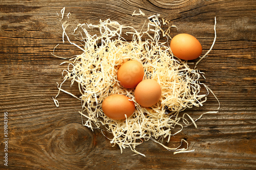 Hay with fresh eggs on wooden background