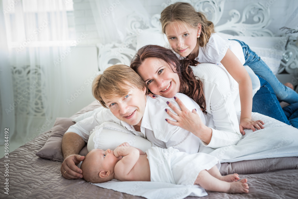 Beautiful positive family mom dad and older daughter and newborn brother in a beautiful and stylish room. Perfect family concept. Advertising concept