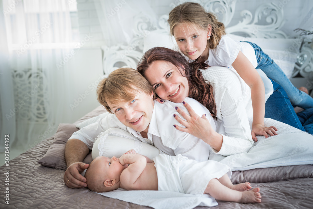 Beautiful positive family mom dad and older daughter and newborn brother in a beautiful and stylish room. Perfect family concept. Advertising concept Beautiful positive family mom dad and older daughter and newborn brother in a beautiful and stylish room. Perfect family concept. Advertising concept