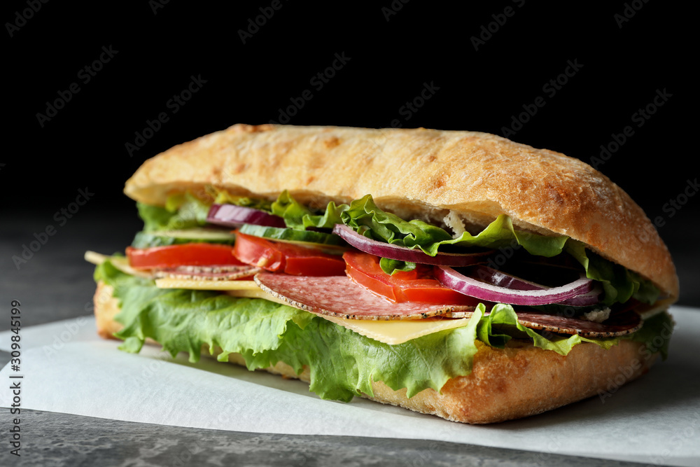 Delicious sandwich with fresh vegetables and salami on grey table, closeup Delicious sandwich with fresh vegetables and salami on grey table, closeup