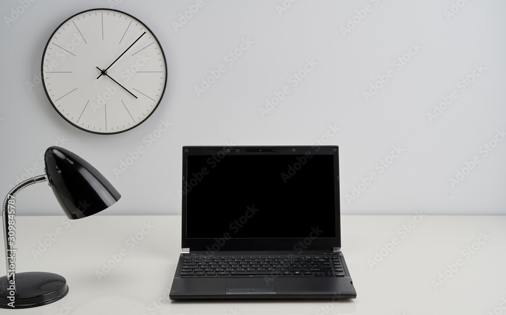 Blank laptop, lamp and clock on the wall in office Blank laptop, lamp and clock on the wall in office