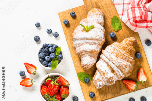 Croissant with fresh berries and cup of coffee.