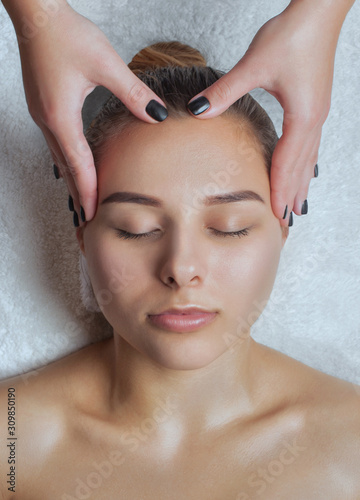 Masseur makes a relaxing massage on the face, neck, shoulders and collarbones of a young beautiful woman in a spa. Cosmetology and massage concept.