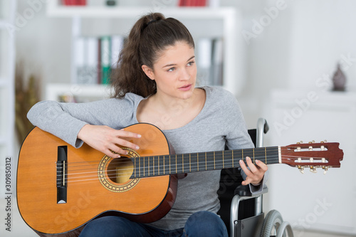 young handicapped guitarist woman sitting on wheelchair