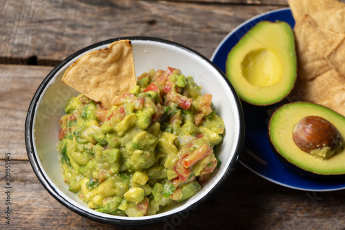 Mexican guacamole with tomato on wooden background