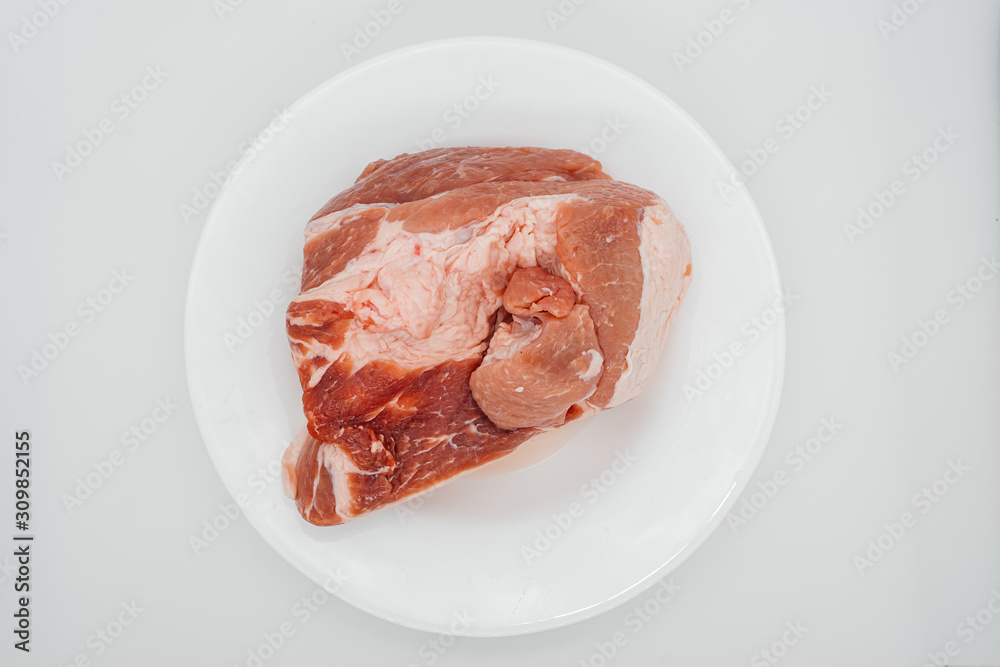 A piece of raw meat on a white plate