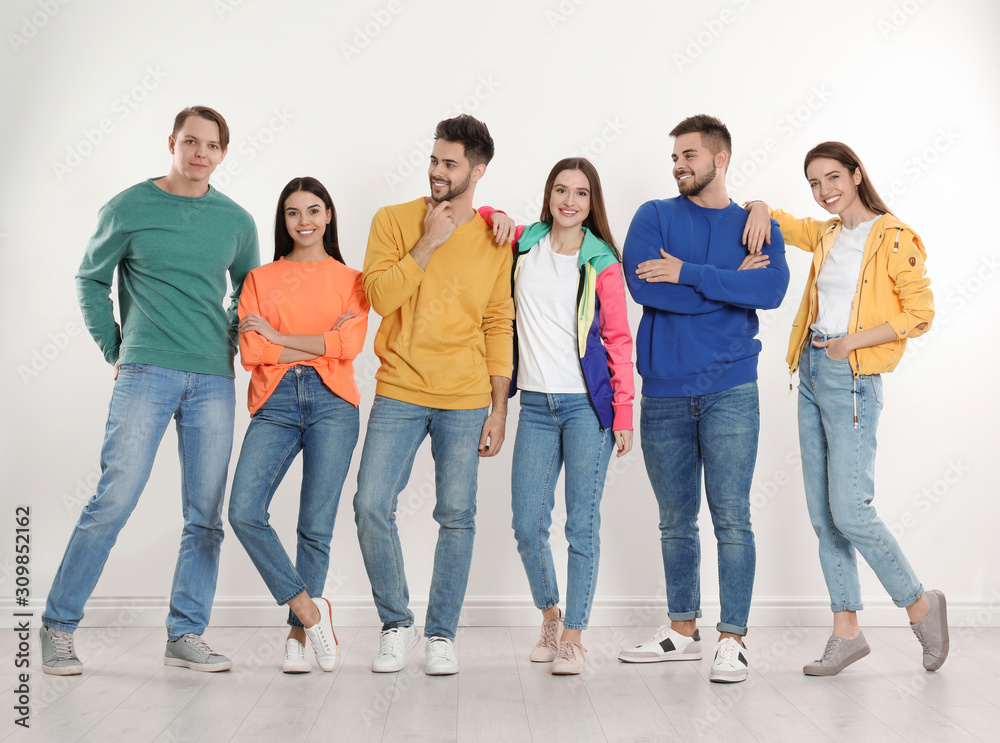 Group of young people in stylish jeans near white wall