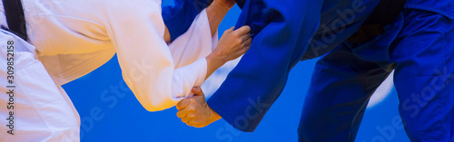 Two judo fighters in white and blue uniform. Martial arts competition - sambo, judo, karate, jiu jitsu, wrestling photo
