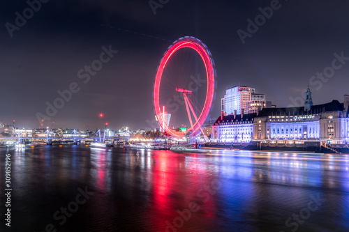 Long exposure of the London eye along the Thames at night with red circle