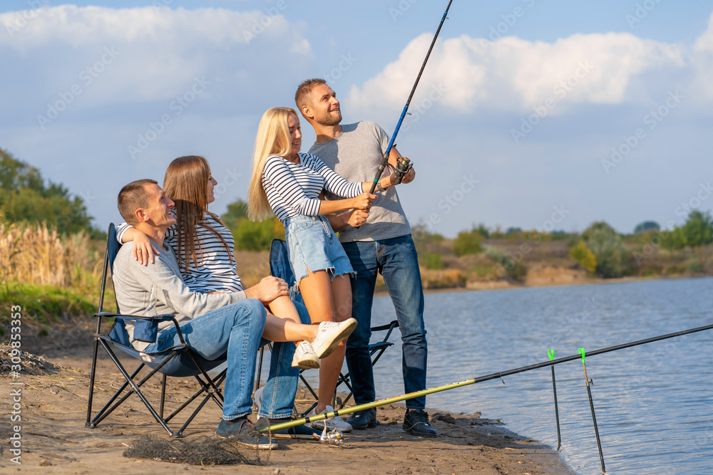 Group of young friends fishing on the pier by lakeside Group of young friends fishing on the pier by lakeside