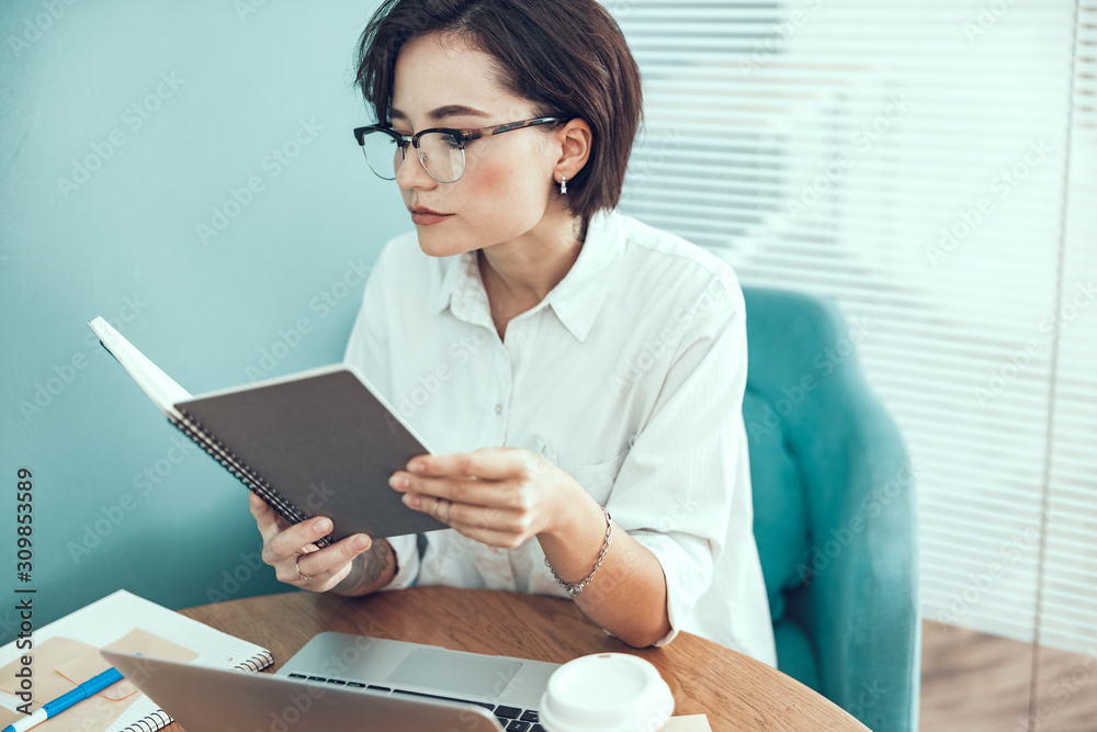 Young woman is holding notebook at the table Young woman is holding notebook at the table