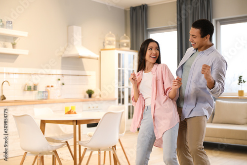 Lovely young interracial couple dancing at home. Space for text