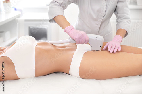 Young woman undergoing laser epilation procedure in beauty salon, closeup