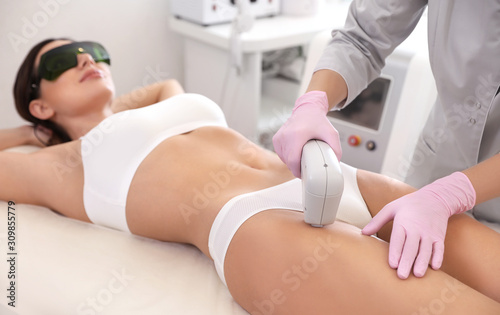 Young woman undergoing laser epilation procedure in beauty salon photo