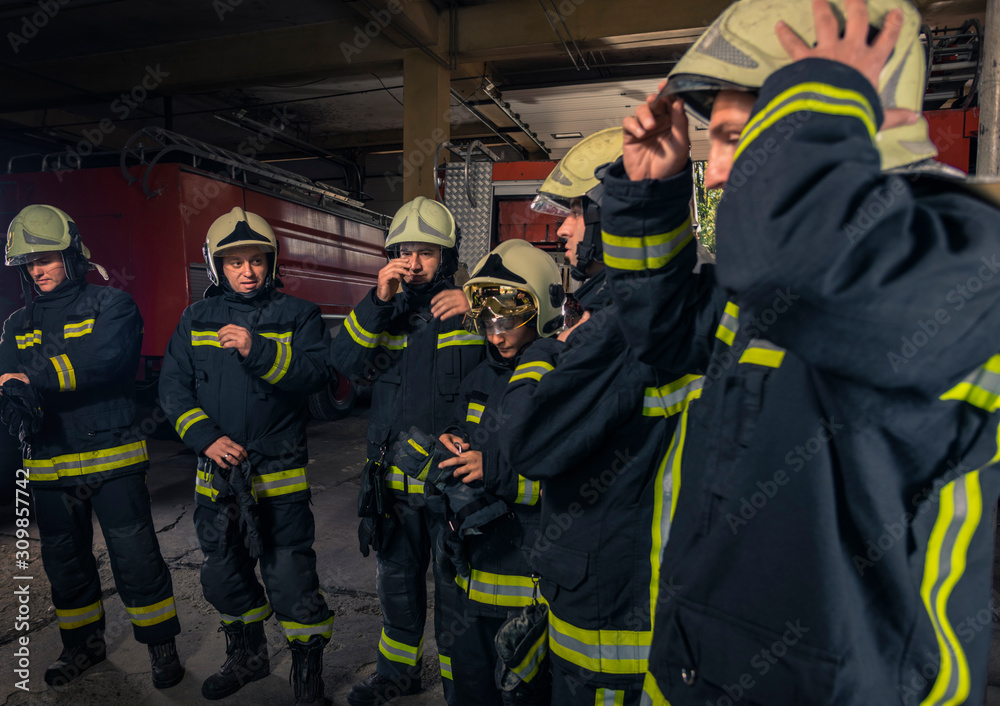 Fototapeta premium Firemen preparing for emergency service. Firefighters putting on gloves.