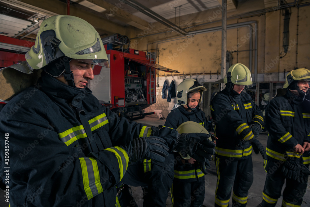 Fototapeta premium Firemen preparing for emergency service. Firefighters putting on gloves.