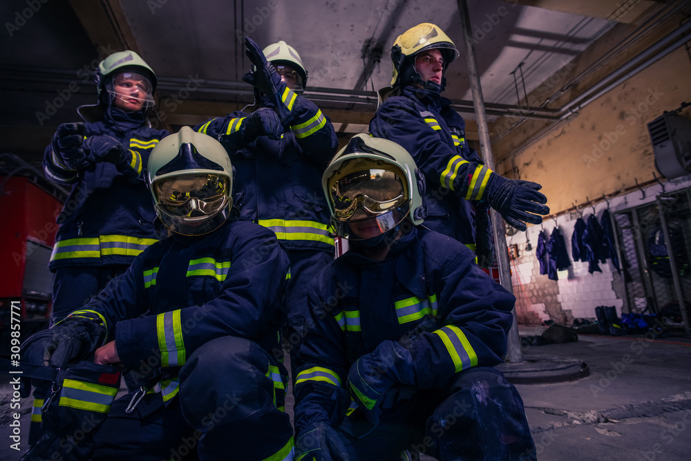 Portrait of group firefighters in front of firetruck inside the fire station Portrait of group firefighters in front of firetruck inside the fire station