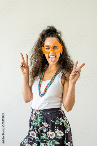Young woman smiling wearing carnival glasses and necklaces on white background