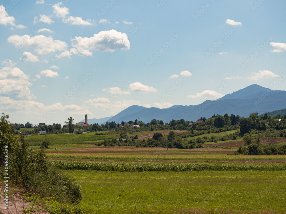 Paisajes de campo y naturaleza rurales con un campanario nubes y montañas al fondo  en la zona de Lipovac , Croacia, verano de 2019