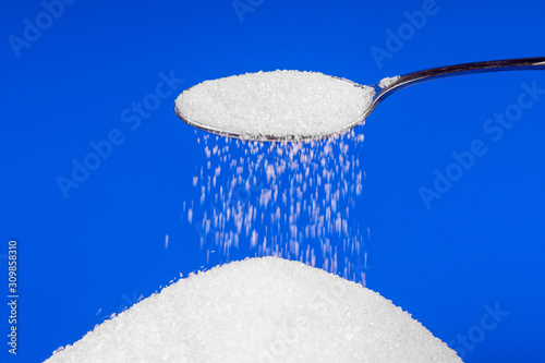 Falling sugar from a spoon on a blue background