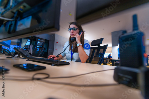 Female security guard operator talking on the phone while watching the computer ( cctv monitors ). photo