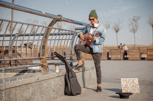 Stylish guy with guitar standing in the city © Yakobchuk Olena