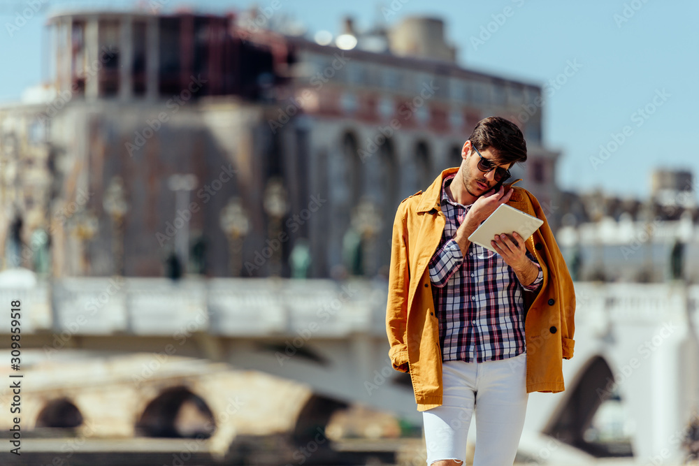 Fototapeta premium Stylish man relaxing while walking at boardwalk near river