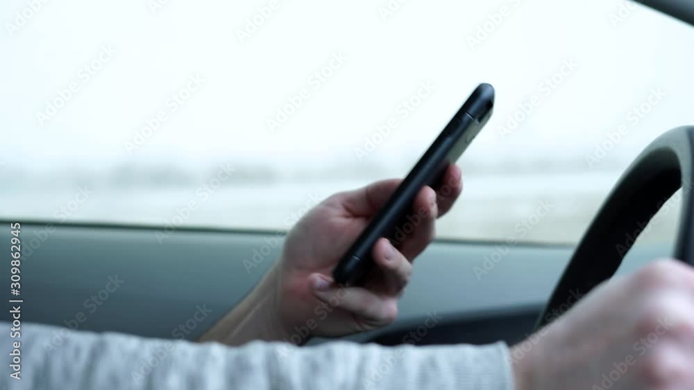 Man with cell phone texting while driving in snowy wet conditions on the highway being irresponsible, dangerous, selfish, lazy, and reckless