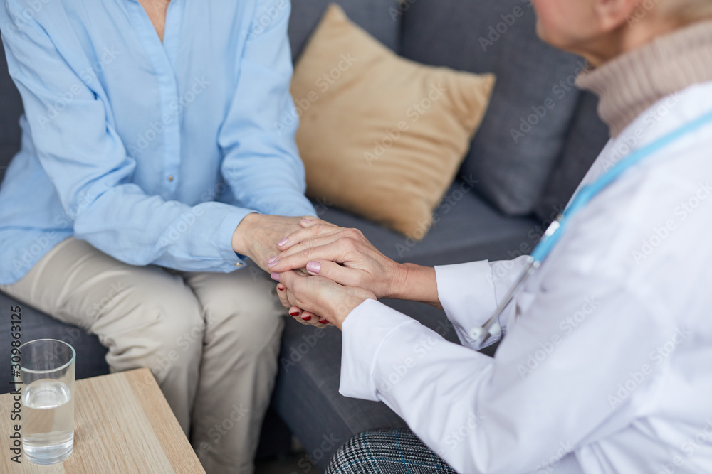 High angle closeup of unrecognizable female doctor holding hands of mature woman while comforting her during consultation in medical clinic, copy space High angle closeup of unrecognizable female doctor holding hands of mature woman while comforting her during consultation in medical clinic, copy space