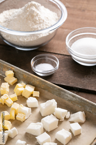 Sheet tray of butter and shortening beside bowls of baking ingredients