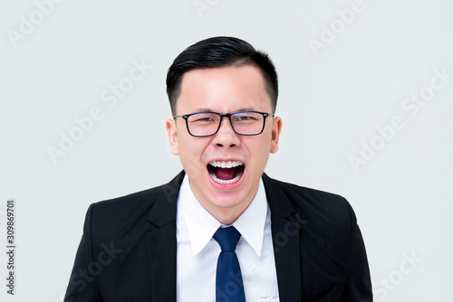 Angry Asian businessman screaming isolated on gray background