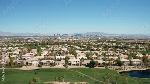 Aerial dolly shot of Las Vegas suburban homes, golf course with city skyline