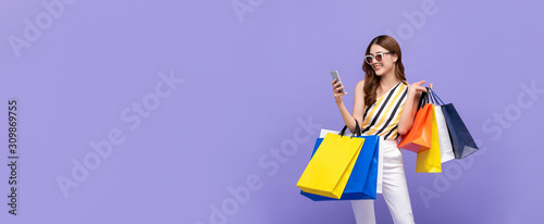 Beautiful Asian woman carrying colorful bags shopping online with mobile phone photo