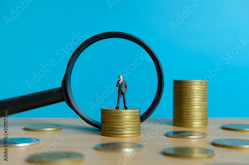 Miniature business concept - thinking businessman looking for financial solution