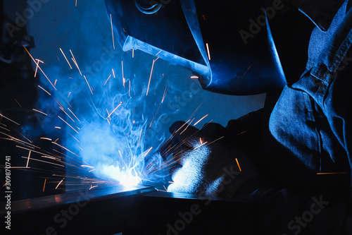 factory welder welds parts with a semi-automatic welding machine