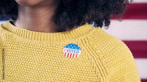 Young Gen Z African American Woman Puts On I Voted Sticker Close Up
