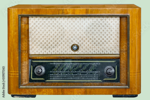 Old tube tabletop radio in wooden case, on isolated pale green background with clipping path.