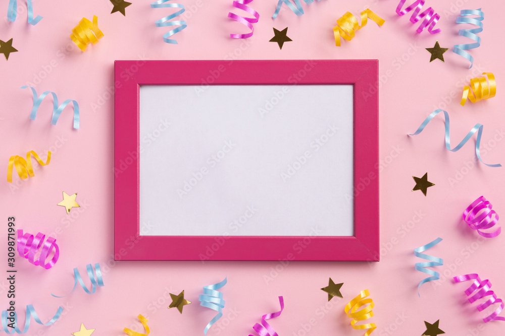 Photo frame, holiday concept. Colorful serpentine and golden stars, on pink  background. Flat lay, top view, copy space.