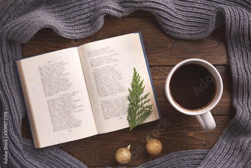 Winter, cozy composition. Warm scarf, book and cup of coffee, on wooden background. Flat lay, top view, copy space.