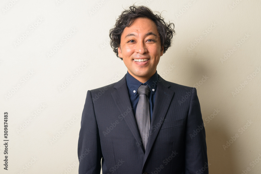 Face of happy Japanese businessman in suit with curly hair smiling Face of happy Japanese businessman in suit with curly hair smiling
