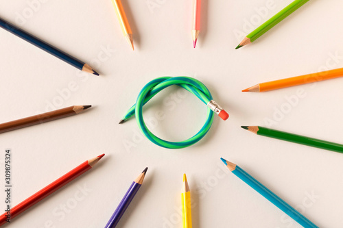Colored pencils with one flexible pencil on white background. The concept of flexibility in decision-making. photo