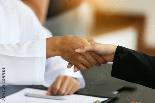 Front view of an Arab businessman and marketer handshaking in office hand shaking on business deal.