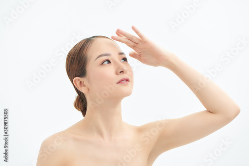Portrait of young Asian woman looking to the side and showing hand on white background.