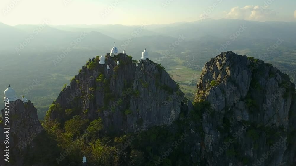 Spectacular aerial view of floating pagodas on the mountain cliff at Wat Chaloem Phra Kiat in Chae Hom District, Lampang province, Thailand. 4K drone video