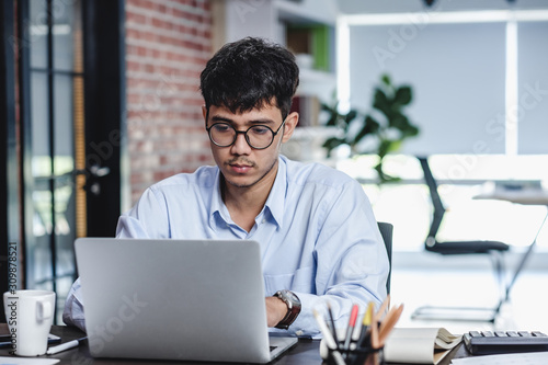 asian businessman woking with laptop and paper work on desk at office.digital workflow online business lifestyle concept.