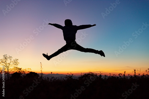 Silhouette of happy people jumping playing on mountain at sunset